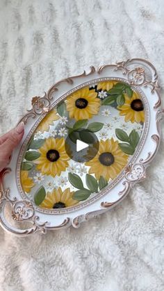 a hand holding a tray with sunflowers painted on it