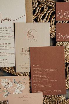 the wedding stationery is laid out on top of some woven material, including cards and envelopes