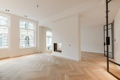 an empty room with wood flooring and large windows in the back ground, next to a fire place