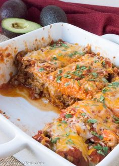 a casserole dish with meat, cheese and vegetables in it next to an avocado