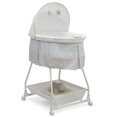 a white baby crib with a teddy bear in it's seat on wheels