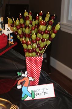 a table topped with apples and grapes in a vase