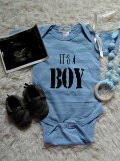 it's a boy bodysuit and shoes are laying on the floor next to an album