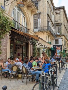 many people are sitting at tables outside on the sidewalk