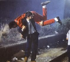 a man is doing tricks on the train tracks with his legs in the air while another man holds him upside down