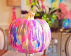 a colorful painted pumpkin sitting on top of a table