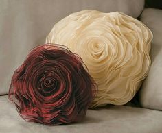 two decorative pillows on a couch with one red and the other beige flowered pillow