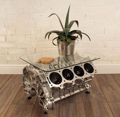 the engine block is made from metal and sits on top of a wooden table with a potted plant