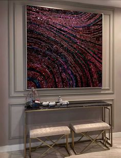 a console table with two stools and a large painting on the wall behind it