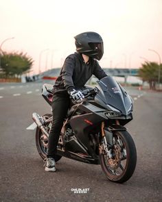 a person sitting on a motorcycle in the middle of an empty parking lot wearing a helmet and gloves