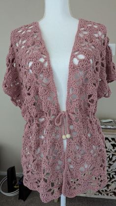 a pink crocheted cardigan on a mannequin