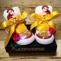 a pair of shoes with princesses on them are sitting in a box and have yellow ribbon