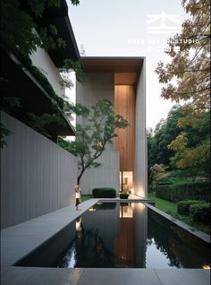 a pool in front of a building with trees and bushes on the other side of it