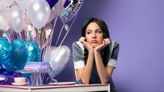 a woman sitting at a table with balloons in the background