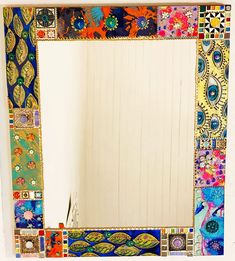 a bathroom mirror with colorful tiles on the bottom and sides, in front of a white wall