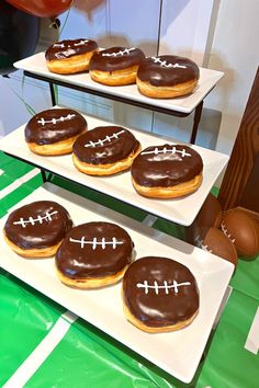 three trays filled with chocolate covered donuts on top of green and white table cloth