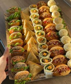 a long tray filled with lots of different types of sandwiches and wraps on top of each other