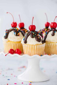 three cupcakes with chocolate frosting and cherries on top