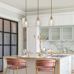 a kitchen with marble counter tops and pink velvet chairs