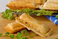 two pastries sitting on top of a wooden cutting board next to green leafy plants