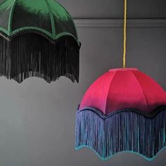 two colorful umbrellas hanging from the ceiling with tassels on each one side