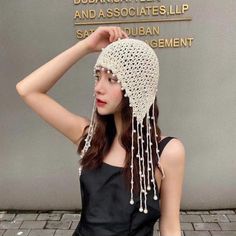 a woman wearing a white crochet hat with beads on it's head