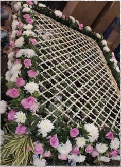 flowers are arranged on the back of a chair that is covered in netting and rope