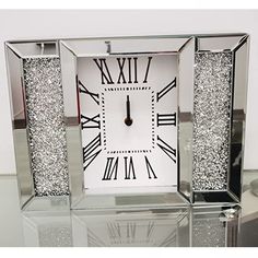 a silver clock sitting on top of a glass table