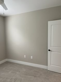 an empty room with a ceiling fan and carpeted floor in front of the door