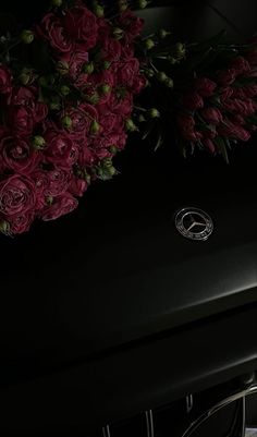 red flowers are sitting on the hood of a black car with mercedes logo and emblem