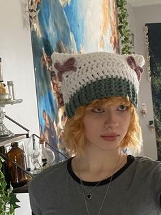 a woman wearing a knitted cat hat in front of a painting