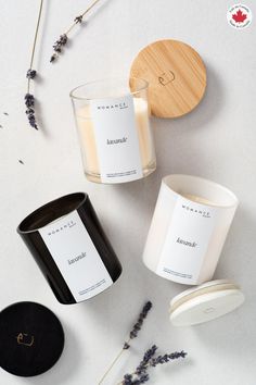 three candles sitting next to each other on top of a white table with lavenders