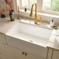 a white sink sitting under a window next to a faucet in a kitchen