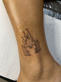 a person with a mickey mouse tattoo on their foot and the word disney written in black ink