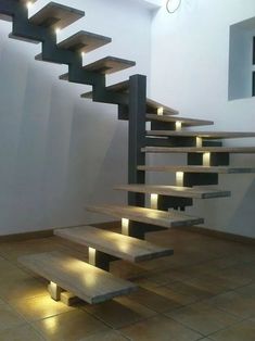 a set of stairs with lights on them in an empty room next to a wall