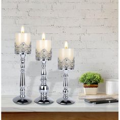 three silver candles sitting on top of a table