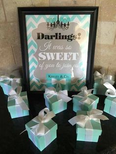 there are many small boxes with bows on the table next to it and a framed sign behind them