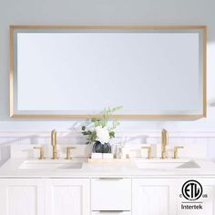 a bathroom vanity with two sinks and a large mirror above it, in front of a white wall