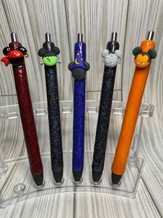 four different colored pens with mickey mouse heads on them, lined up in a clear holder