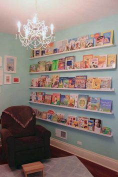 a living room filled with furniture and lots of books on the shelves in front of a chandelier