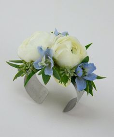 two white roses and blue flowers in a silver vase