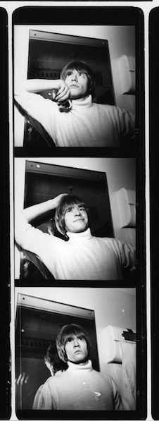 black and white photograph of woman laying on bed with head resting on arm, looking up at camera