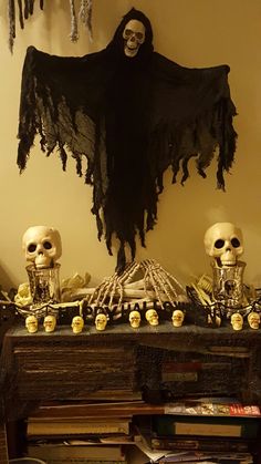 halloween decorations with skeletons and skulls on a table in front of a skeleton wall hanging