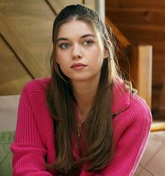 a young woman in a pink sweater sitting on a couch