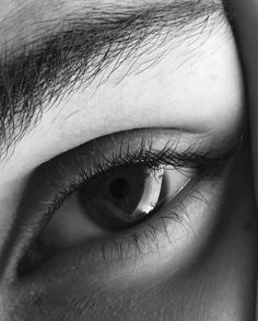 the eye of a person with long hair and large lashes is seen in this black and white photo