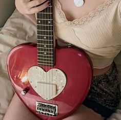 a woman is holding a red heart shaped guitar