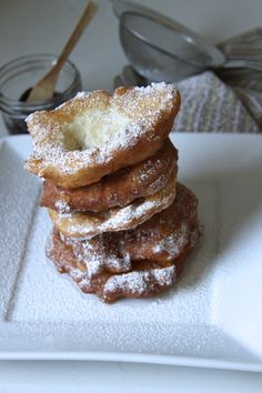 powdered sugar covered donuts stacked on top of each other in a white plate