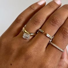 a woman's hand with three different rings on her left and the middle finger