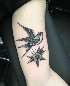 a small tattoo on the arm of a woman with a bird and flower in it