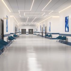 an empty hospital hallway with blue chairs and paintings on the walls, along with white flooring